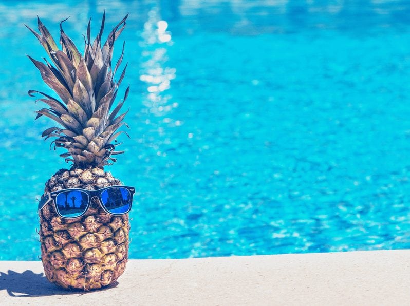pineapple with sunglasses by a pool