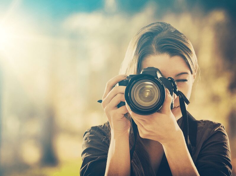 Portrait of a female photographer looking into the viewfinder of a camera